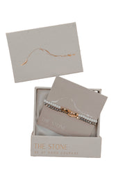 Two beaded stretch bracelets displayed in an open gift box with gold foil print, with the brand name 'THE STONE' on the packaging.