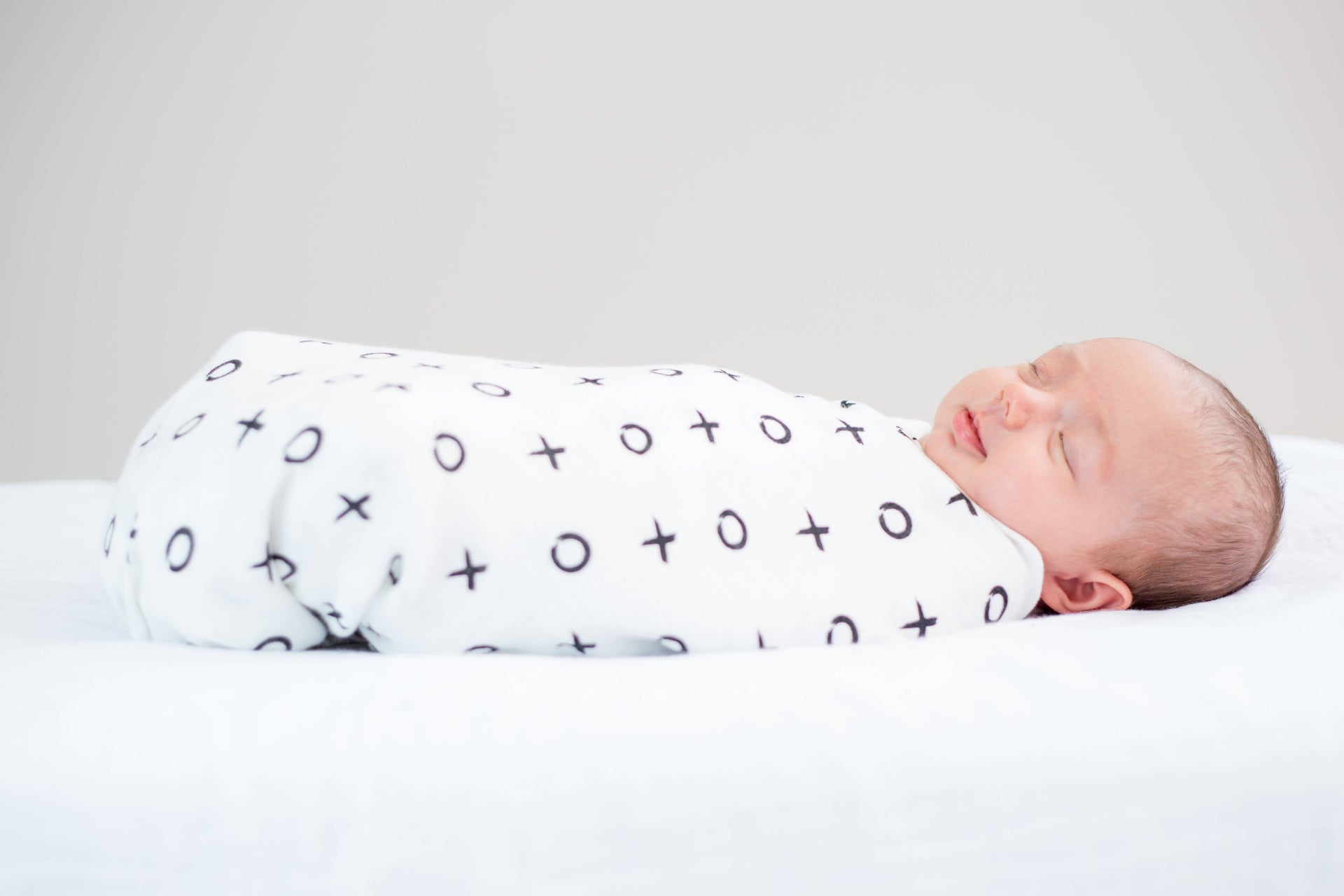 XO muslin swaddle blanket on baby