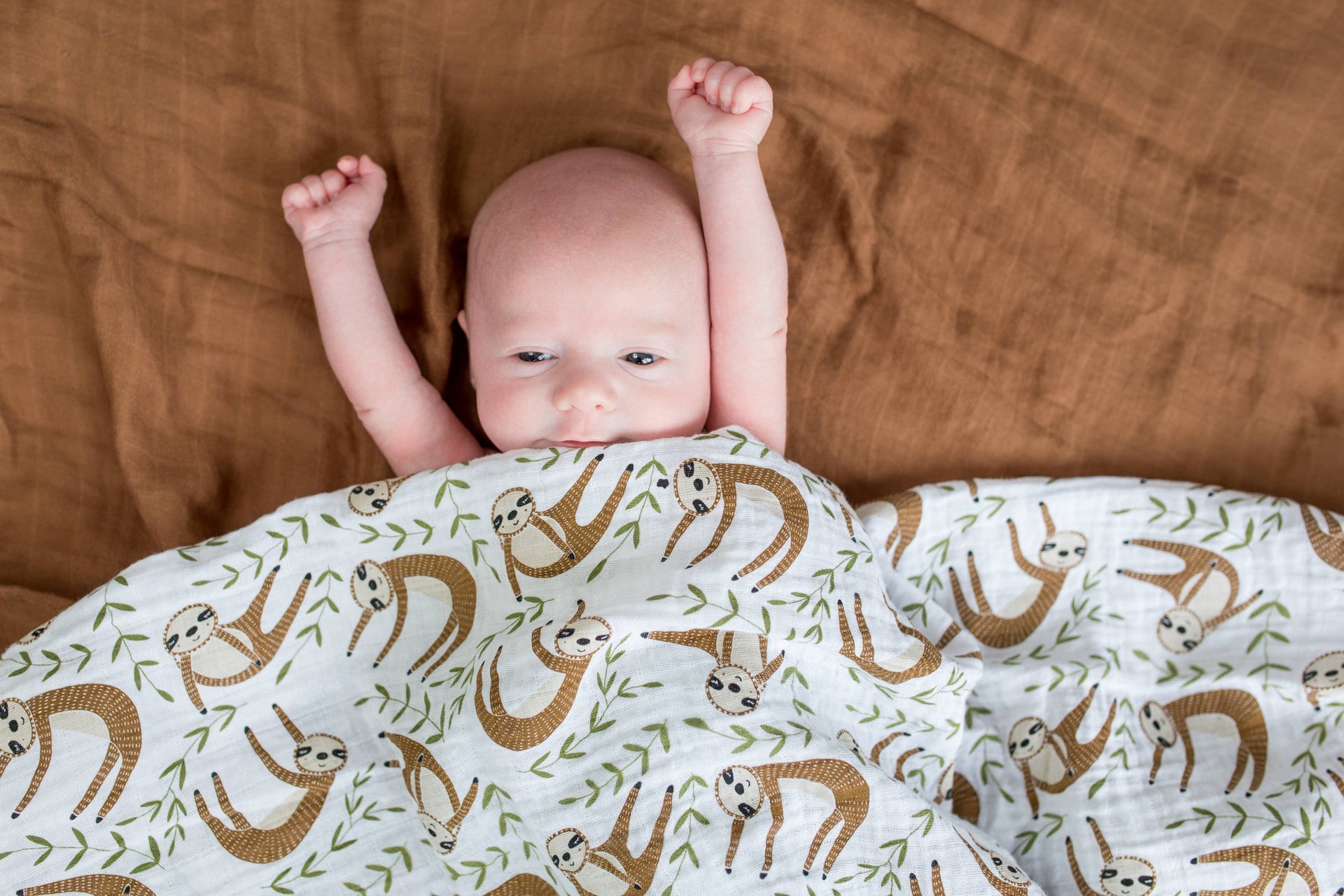 sloth muslin swaddle blanket on baby